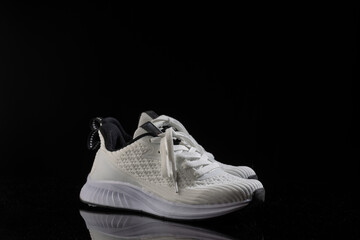 pair of white sneakers rests on a sleek black background showcasing their trendy design and...