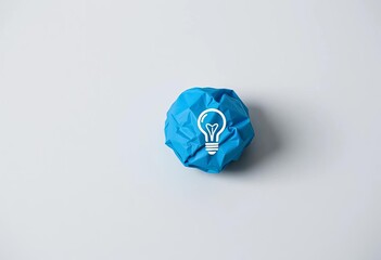 Blue crumpled paper ball with light bulb icon on gray background symbolizing creative ideas, texture, blue