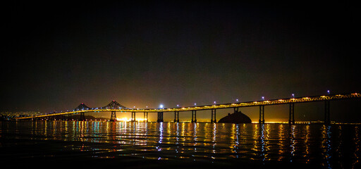
Night view of bridge over water with light reflections.