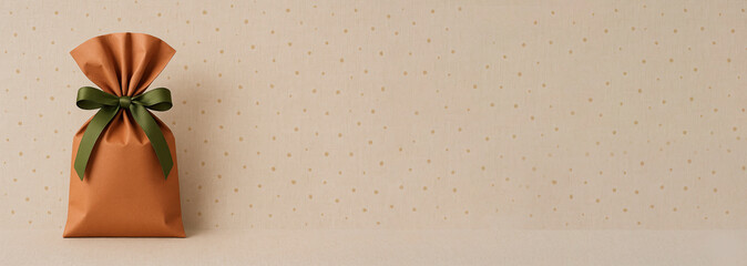 Gift bag with green ribbon on beige background with gold polka dots