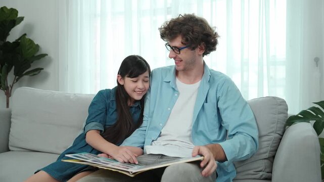 Happy dad telling story and moving gesture while funny schoolgirl pointing at story book. Student listen and enjoy talking about fairytail while looking parent. Family recreation concept. Pedagogy.
