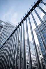 Obraz premium Upward Perspective of Metallic Fence Against City Skyscrapers, Blue Sky.