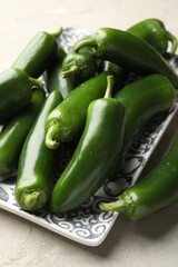 Fresh jalapeno peppers on light textured table, closeup