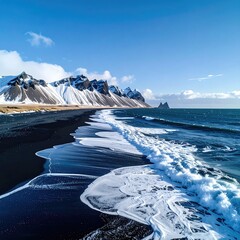 Black sand beach meets turquoise waves, snow-capped mountains under a vibrant blue sky