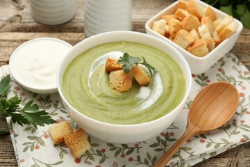 Tasty broccoli cream soup with croutons served on wooden table, closeup
