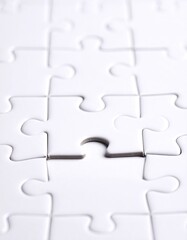Close-up of a nearly complete white jigsaw puzzle with a single missing piece in the center