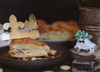 One bitten piece of galette in a plate with a toy on a dark table.
