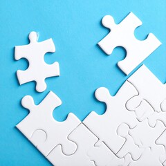 Obraz premium White jigsaw puzzle pieces on a light blue background, two pieces separated, suggesting incompletion or a solution
