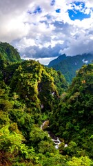 Obraz premium Lush valley with dramatic mountains and clouds