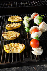 Grilling vibrant yellow squash slices and skewers loaded with tomatoes, onions, tomatillos, peppers, releasing smoky flavors on barbecue grate
