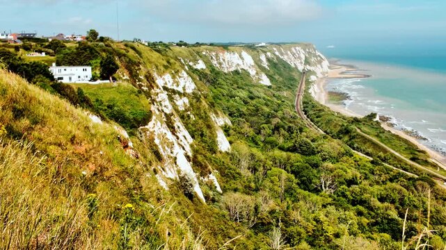 Rugged coast and railway line, Folkestone, Kent, England, UK, with chalk cliffs, sea views and tracks curving along the shoreline
