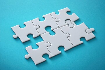 Fototapeta premium Close-up of partially assembled white puzzle pieces on a bright blue surface conveying problem solving and teamwork