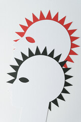 silhouette heads in profile machine-cut from white paper and arranged in overlapping form with rays