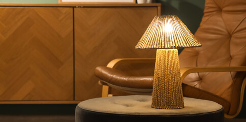 Glowing lamp on pouf in living room at night