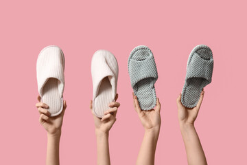 Female hands holding different woman's slippers on pink background