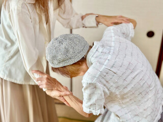 高齢女性の手首を持って補助する女性