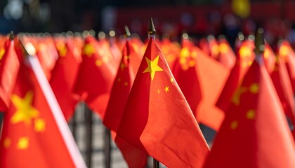 A close-up showcases numerous small, vibrant red flags with yellow stars, set outdoors in a sunny environment, creating a repetitive patriotic display