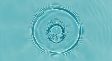 A single water drop creating concentric ripples on a clear blue water surface, viewed from directly above