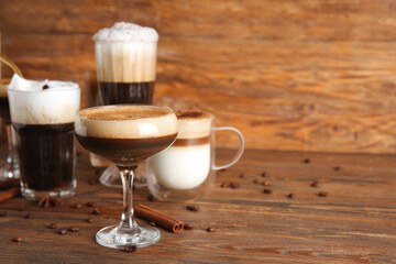 Glasses of hot coffee with cinnamon and star anise on wooden background