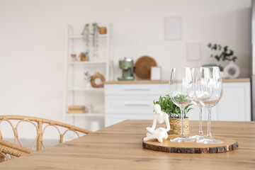 Glasses, figure and houseplant on dining table in light kitchen, closeup