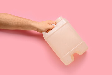 Male hand holding canister on pink background