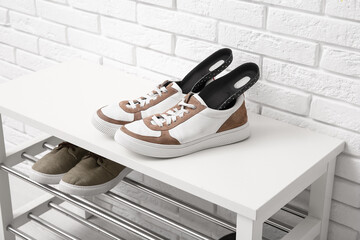 Sneakers with orthopedic insoles on bench near white brick wall in hallway