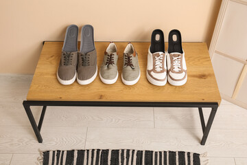 Sneakers with orthopedic insoles on bench near beige wall in hallway