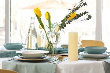Elegant table setting with beautiful tulip flowers and candles near window
