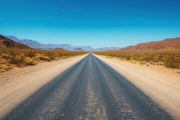 Long straight road stretching into the distance through a dry desert landscape with arid mountains and clear blue sky