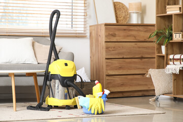 Vacuum cleaners and basin of cleaning supplies with brushes in living room