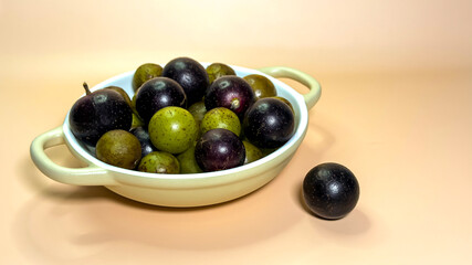 Fresh grapes in ceramic bowl on beige background