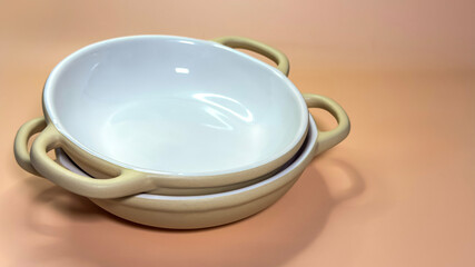 Stack of two ceramic bowls with handles isolated on beige background
