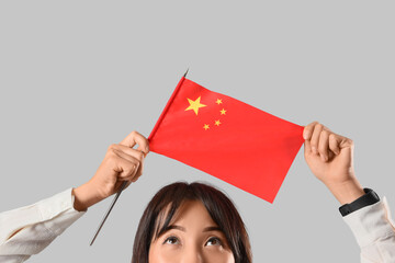 Female Asian teacher with flag of China on grey background, closeup
