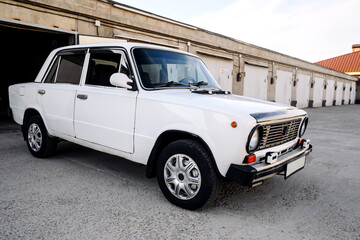 white vintage sedan parked near old garages, side view, transport concept