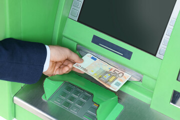 Male hand withdrawing money from ATM outdoors, closeup