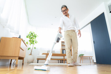 リビングに掃除機をかけるミドルの男性