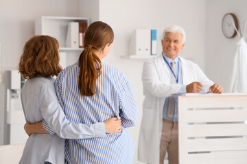 Obraz premium Young lesbian couple hugging after IVF at fertility doctor's office, back view