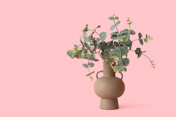 Vase with artificial eucalyptus branches on pink background