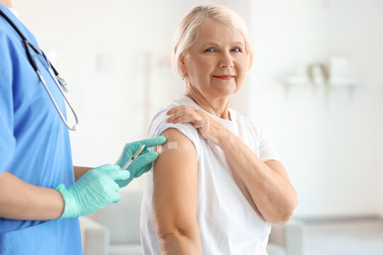 Senior woman receiving medical patch from doctor after vaccination at home - Powered by Adobe