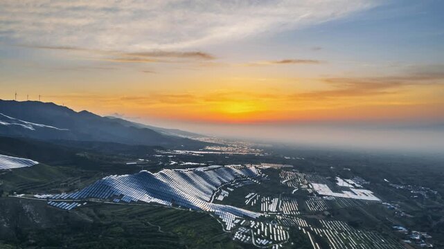 aerial time lapse video of the sunrise over mountainous solar photovoltaic panel arrays, a new energy vista, the combination of natural beauty and renewable energy infrastructure creates a harmonious 