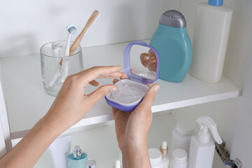 Female hands and box with occlusal splint in bathroom, closeup