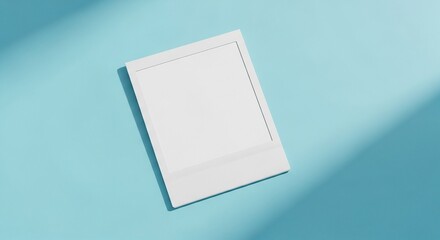 Blank instant photo frame on blue background with sunlight and shadows.