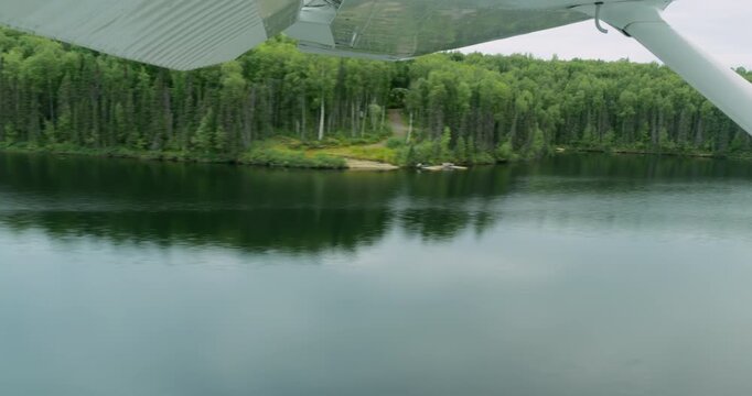 Floatplane landing on the lake calm water in Alaska. View from the inside of the aircraft
