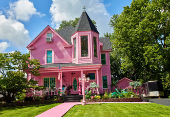 Pink house with bright pink porch and pink sidewalk on a perfect summer day