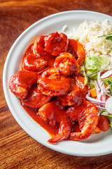 A plate of camarones a la diabla, spicy shrimp cooked in a rich red sauce, served with white rice and a side salad.