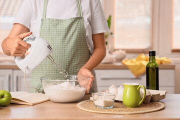 Woman whipping egg whites with mixer in kitchen