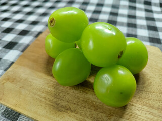 Fresh and vibrant green grapes, known for their crisp texture and sweet flavor, are beautifully displayed on a rustic wooden board, perfect for a healthy snack or delightful dessert