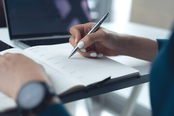 2026 Event planner timetable agenda plan on schedule event. Business woman checking weekly planner, taking note on calendar notebook on office table. Calendar event plan, work planning