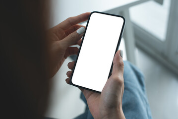 Mockup, woman using mobile phone with white empty screen with office background. Female hand holding smartphone, looking at blank screen for mobile app design and online marketing