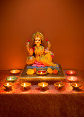 Beautiful statue of Goddess Laxmi with plenty of lit up Diyas. Diwali festival photo with glowing oil lamps and Lakshmi idol.